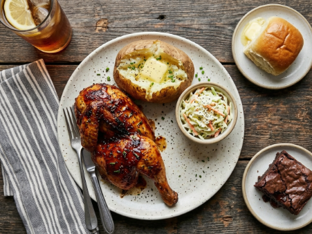BBQ plate with roasted chicken, Potato and coleslaw; separate roll with butter; brownie on its own plate; one fork and one knife.